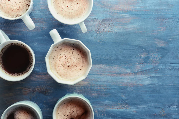 Многие чашки с вкусным ароматным кофе на цветной деревянный стол, плоский лежал
 - Фото, изображение