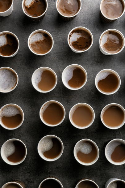 Many plastic cups with tasty aromatic coffee on dark background, flat lay - Photo, Image
