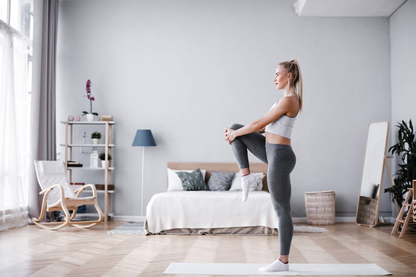 Full length portrait of attractive young woman working out at home, doing pilates exercise on mat. - Fotografie, Obrázek