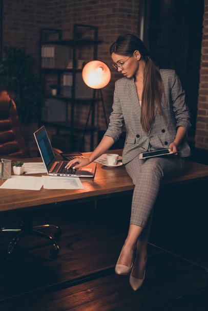 Vertical close up photo attentive she her business lady chief checking look e-reader e-book report information learn study compare analyze sit office table wear specs formal wear checkered suit - Фото, изображение