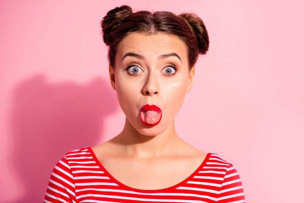 Close up photo beautiful she her lady pretty hairdo two buns bright pomade allure big lips tongue out mouth impolite making faces wear casual striped red white t-shirt isolated pink background - Foto, afbeelding