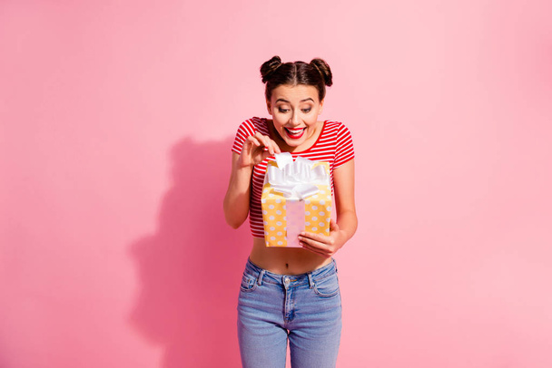 Portrait of her she nice cute charming attractive winsome lovely girlish funny cheerful cheery girl in casual striped t-shirt jeans holding in hands new gift isolated on pink pastel background - Fotografie, Obrázek