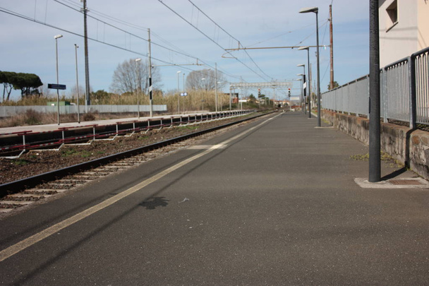 ένα μικρό εγκαταλελειμμένο τοπικό σταθμό κατά τη διάρκεια της ημέρας. πεζοδρόμιο για τους επιβάτες που περιμένουν τα τρένα για τα ταξίδια τους, μεταξύ αναχωρήσεων και αφίξεων - Φωτογραφία, εικόνα