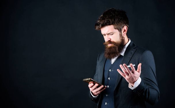 Guy surfing internet smartphone black background. Online service and application. Modern technologies. Businessman well groomed man hold smartphone. Man formal suit use smartphone social networks - Photo, image