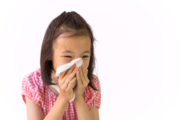 Portrait of cute little girl blowing nose in paper handkerchief,Asian girl sneezing in a tissue isolated on white background,hay fever, runny nose,concept of pollution,dust allergies - Φωτογραφία, εικόνα