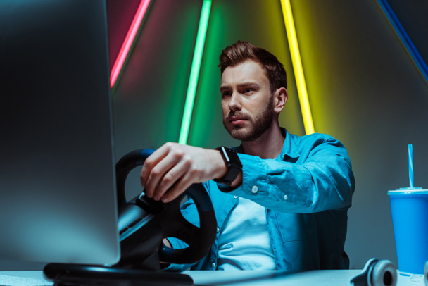 selective focus of handsome and good-looking man playing video game with steering wheel - Foto, Bild