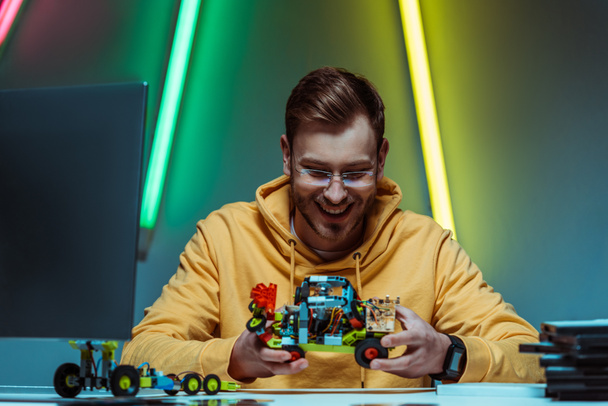 smiling and handsome man in glasses playing with toy constructor  - Photo, image