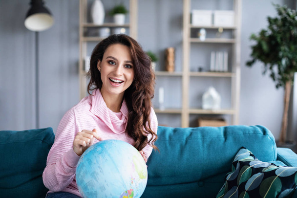 Positive woman points at destination on globe. Traveling concept. - Zdjęcie, obraz