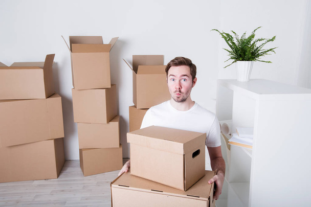 Young man with carton boxes in new apartment. - Photo, Image