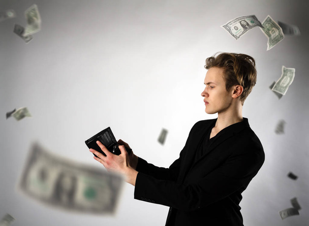 Young man and empty wallet. Currency, expense and income concept - Photo, Image