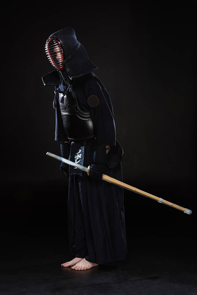 Full length view of kendo fighter with sword bowing on black - Photo, Image