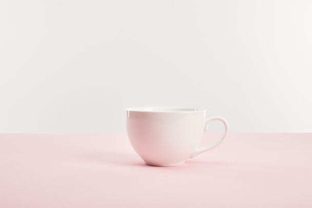 taza blanca con bebida en la superficie rosa aislado en gris
  - Foto, Imagen