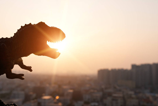 silhouette du tyrannosaure et des bâtiments au coucher du soleil
 - Photo, image