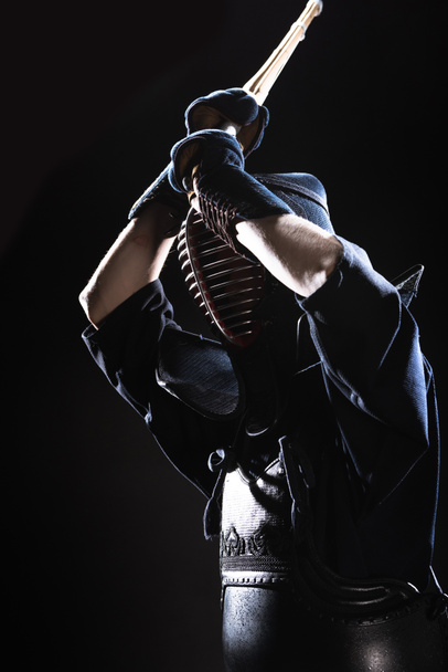 Μαχητής kendo με πανοπλία εξάσκηση με ξίφος μπαμπού σε μαύρο - Φωτογραφία, εικόνα