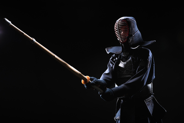 Bojovník Kendo v brnění, cvičí s bambusovým mečem izolované na černém pozadí - Fotografie, Obrázek