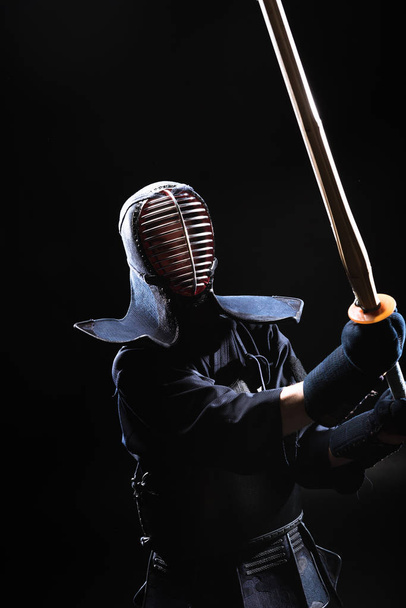 Kendo-Kämpfer in Rüstung übt mit Bambusschwert auf Schwarz - Foto, Bild