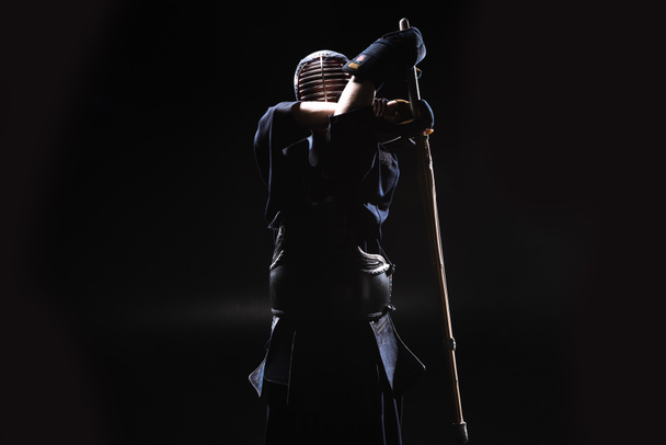 Kendo fighter in armor practicing with bamboo sword on black - Φωτογραφία, εικόνα