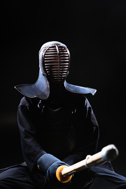 Μαχητής kendo με κράνος, κρατώντας ξίφος μπαμπού σε μαύρο - Φωτογραφία, εικόνα