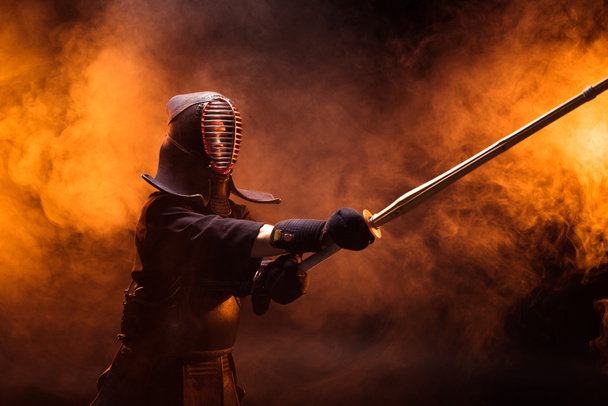 Kendo fighter in armor practicing with bamboo sword in smoke - Photo, Image