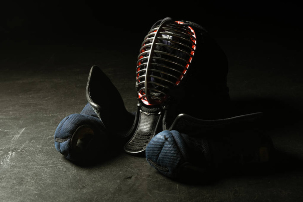 Kendo-Handschuhe und traditioneller Helm auf dunkler Oberfläche - Foto, Bild