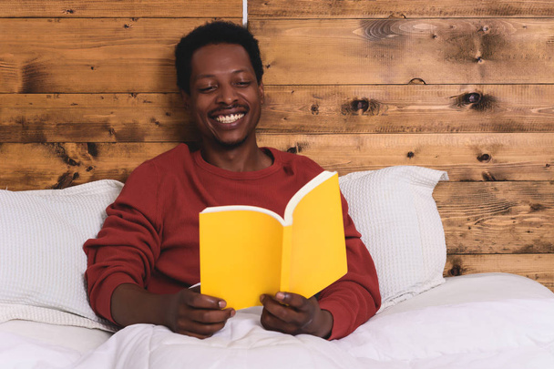man laying in bed and reading book - Valokuva, kuva