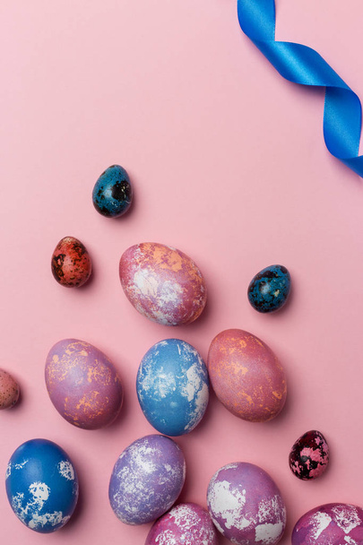 Holiday Easter eggs with white and blue ribbon on pink background - Fotó, kép