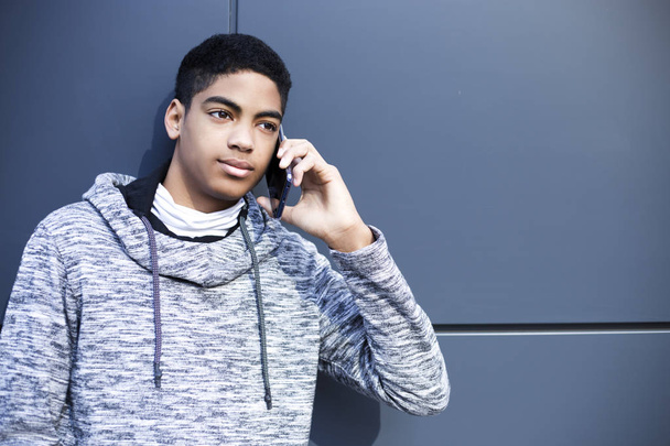 Fekete fiatalember beszél az okostelefonon. Az afro-amerikai fiú mobiltelefont használ.. - Fotó, kép