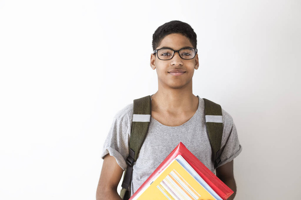 Portret van Afrikaans-Amerikaanse student in glazen met boeken. Zwarte jonge man lacht staat op de straat Holding schoolboeken in zijn handen.   - Foto, afbeelding