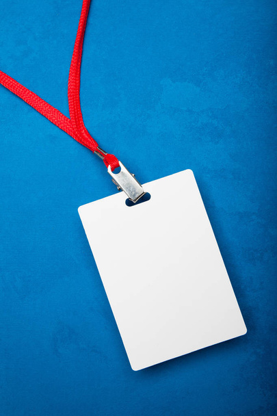 Empty white blank badge on blue background with red neck. - Φωτογραφία, εικόνα