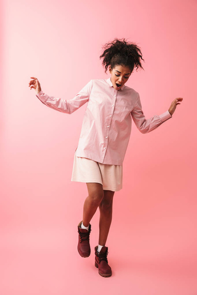 Young african woman posing isolated over pink wall background screaming. - 写真・画像