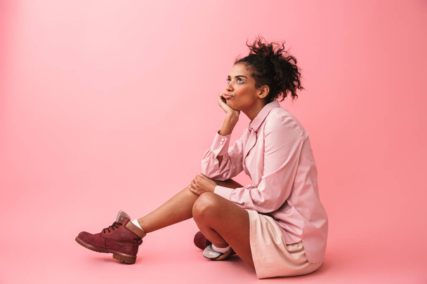 Pretty tired bored young african woman posing isolated over pink wall background. - 写真・画像
