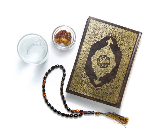 Quran heilig boek, water, dadels en rozenkrans, geïsoleerd op wit - Foto, afbeelding