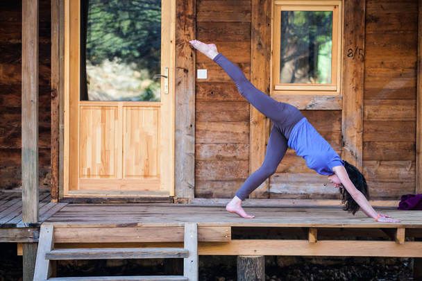 Una mujer practica yoga en el porche de una antigua casa de madera
. - Foto, imagen