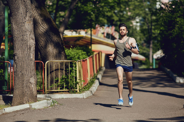 A male runner runs along the road to the park. - 写真・画像