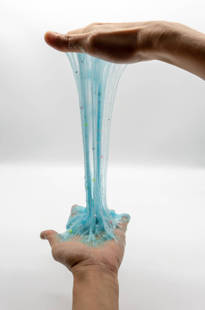 mano strecthing transparente azul brillo limo aislado en blanco
 - Foto, imagen
