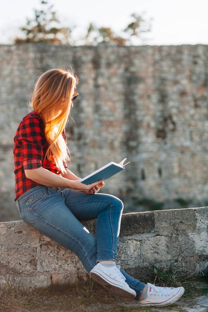Mujer joven disfrutando leyendo un libro en el parque público
 - Foto, Imagen