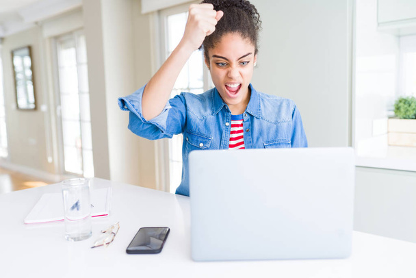 Young african american student woman using computer laptop annoyed and frustrated shouting with anger, crazy and yelling with raised hand, anger concept - Photo, image