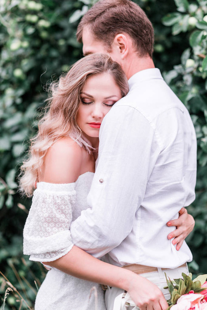 Sposo e sposo con un mazzo di peonie in posa sullo sfondo della foresta
 - Foto, immagini