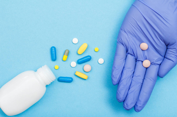 Közelről palack különböző tabletták és kapszulák és kezét a női orvos kesztyű és tabletták a tenyér. - Fotó, kép