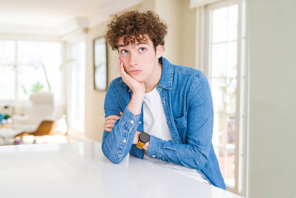 Young handsome man wearing casual denim jacket at home thinking looking tired and bored with depression problems with crossed arms. - Photo, image