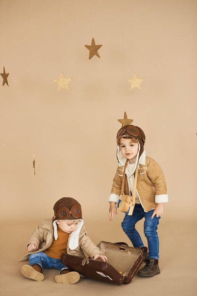 two brothers are played with a toy airplane and a suitcase on a  - Foto, Imagem