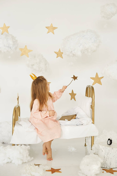 Μικρή πριγκίπισσα με το μαγικό ραβδί στο κρεβάτι σε ένα σύννεφο  - Φωτογραφία, εικόνα