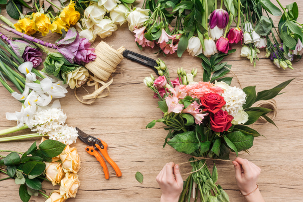 Cropped view of florist making flower bouquet on wooden surface - Foto, Imagem