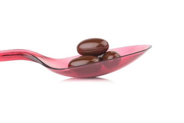 E. élelmiszer-kiegészítő vitamin. barna színű kapszula. piros kanalat - Fotó, kép