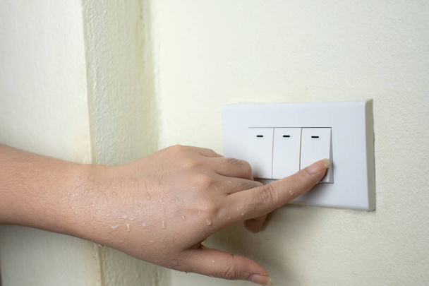 Humide main allumer les lumières interrupteur électrique, ne pas éteindre l'alimentation tandis que les mains humides peuvent concept de choc électrique
 - Photo, image