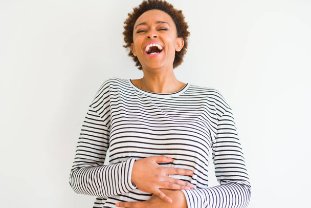 Jovem mulher americana africana bonita vestindo listras suéter sobre fundo branco Sorrindo e rindo duro em voz alta, porque engraçado piada louca. Expressão feliz
. - Foto, Imagem