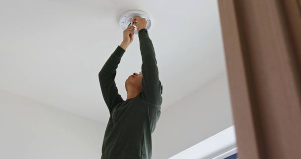 Mężczyzna zainstalować lampę na suficie w domu - Zdjęcie, obraz