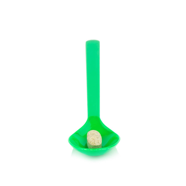 Cuchara de plástico verde con ajo suplementario aislado en blanco
 - Foto, Imagen