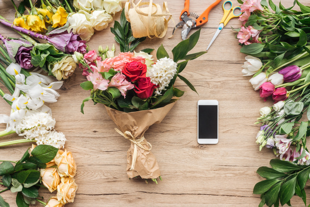 Flores frescas e smartphone com tela em branco na superfície de madeira
 - Foto, Imagem