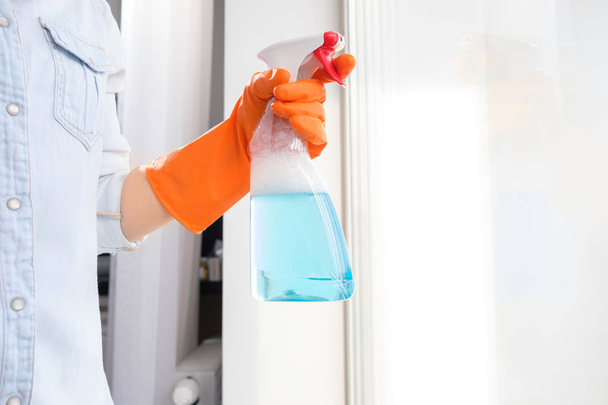 Girl washes a glass in orange gloves with a blue rag - Foto, Imagen